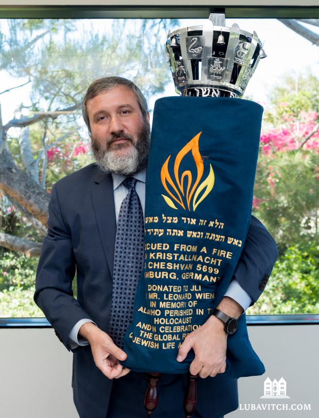 Rabbi Reuven Mintz holds a Torah rescued during Kristallnacht in Hamburg, Germany