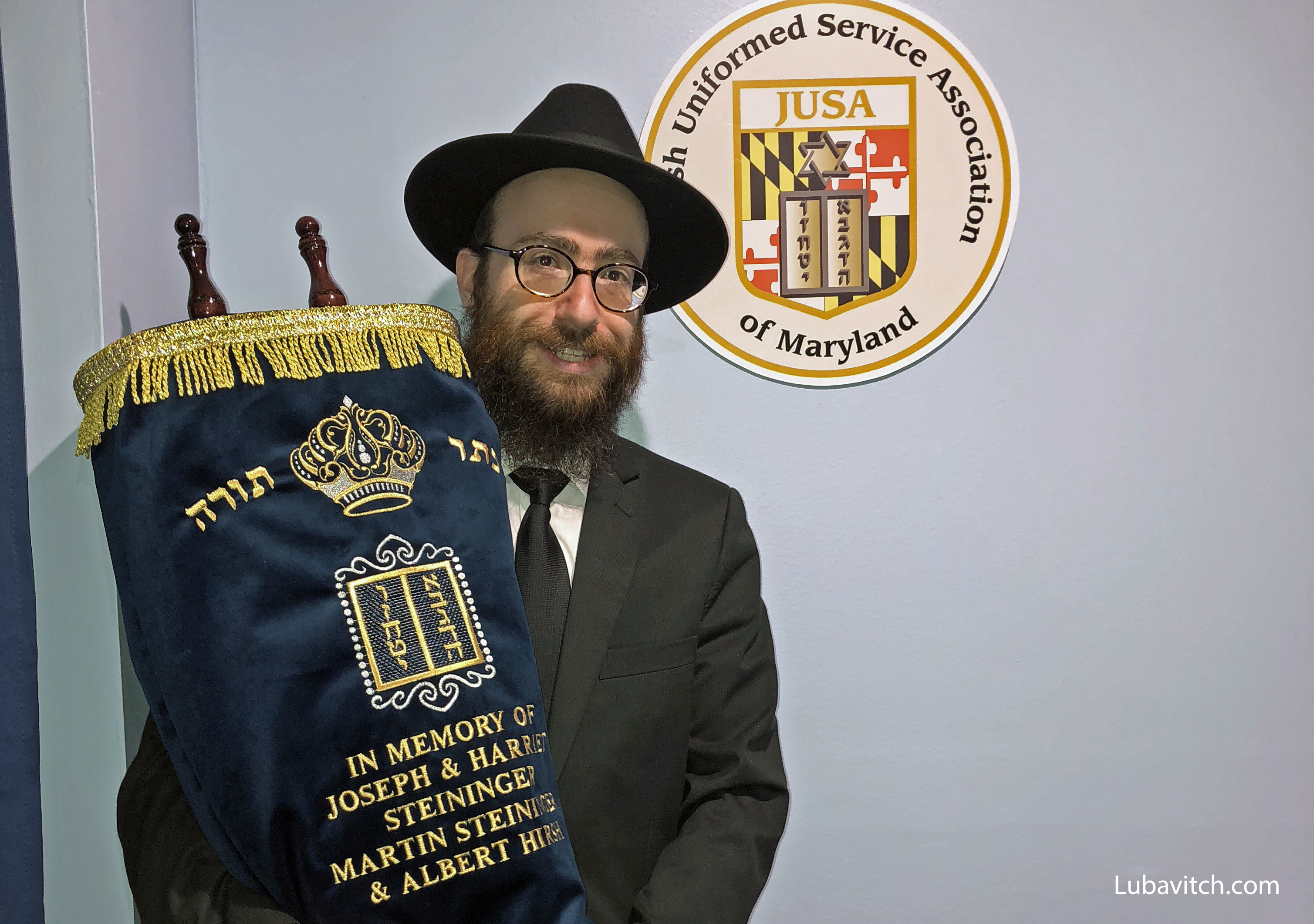 Rabbi Chesky Tenenbaum holds the Steininger Torah, dedicated to veterans
